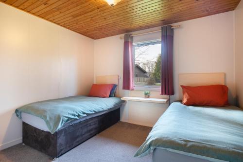 two twin beds in a room with a window at Hunters Quay -3 Bedroom Lodge in Kirn