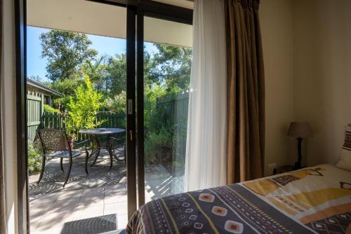 a bedroom with a sliding glass door to a patio at Forest Cove cottage in Knysna