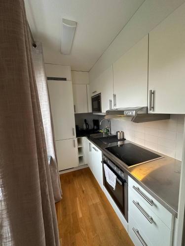 uma cozinha com armários brancos, um lavatório e um fogão em Beautiful And Comfortable Apartment em Gotemburgo