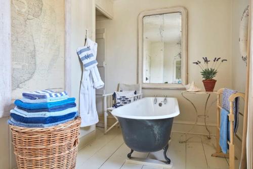 uma casa de banho com um espelho grande e uma banheira em Boho-chic bolthole on the beach - Mariner's Cottage em Deal
