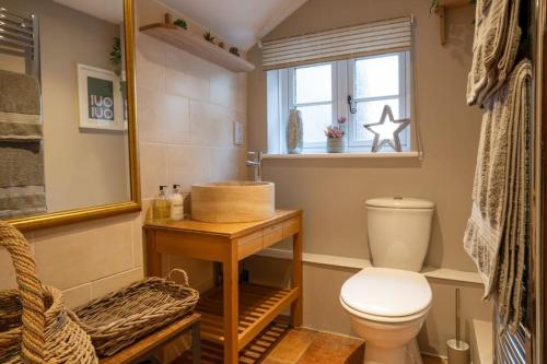a bathroom with a toilet and a sink and a window at Cosy Matlock Cottage with Fireplace, Stunning Views & Pet Friendly in Two Dales