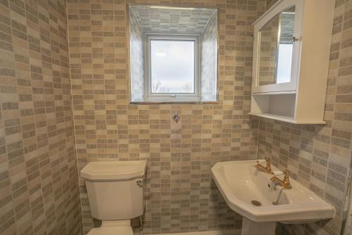 baño con aseo y lavabo y ventana en Rivendell en Holywell