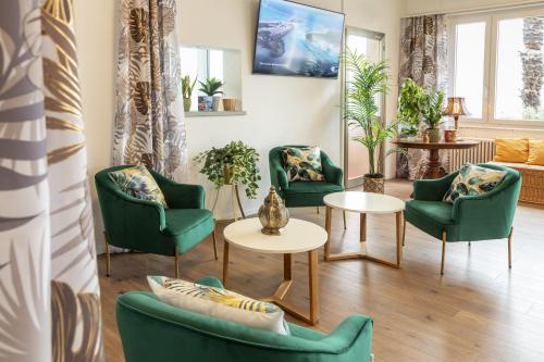 a living room with green chairs and tables at Garden Hotel Primavera in Brissago
