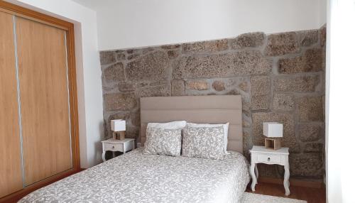 a bedroom with a stone wall with a bed and two night stands at Casa do Sobrado ByAlta 