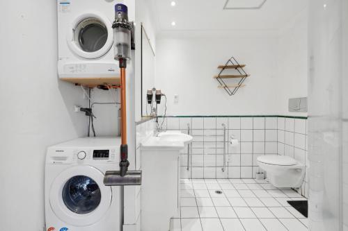 a bathroom with a washing machine and a toilet at The Urban Charmer - Wellington Holiday Apartment in Wellington