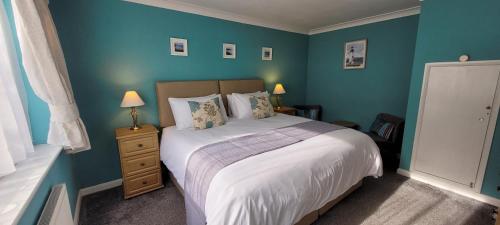 um quarto com uma cama grande e paredes azuis em Churston Way Lodge Guest House em Brixham