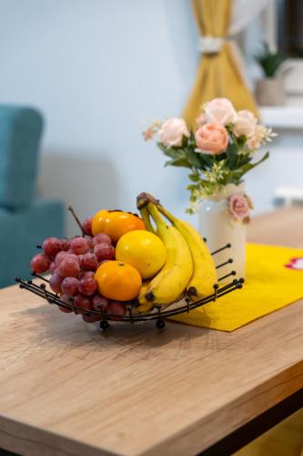 a basket of fruit on a table with a vase of flowers at SkyLine Lux 2 Apartman Zlatibor in Zlatibor