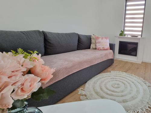 un sofá gris en una sala de estar con flores en La Casuță, en Dej