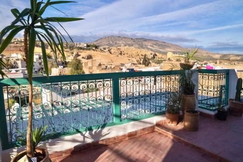 a balcony with a green fence and a palm tree at Dar Sunrise Fes in Fès