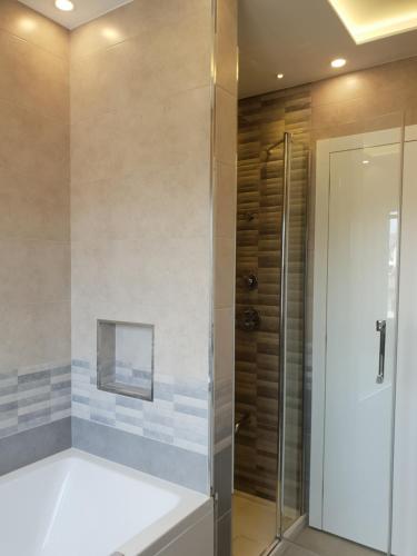 La salle de bains est pourvue d'une douche à l'italienne à côté d'une porte en verre. dans l'établissement 2 Ljubljana Modern Villa Apartment, à Ljubljana