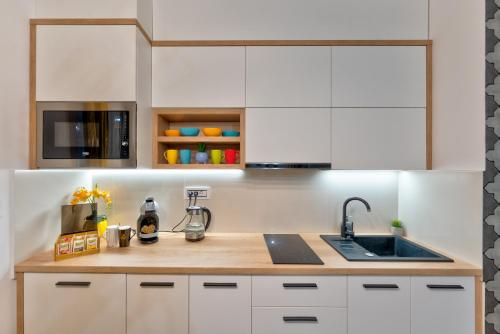 a kitchen with white cabinets and a sink at SkyLine Lux 2 Apartman Zlatibor in Zlatibor