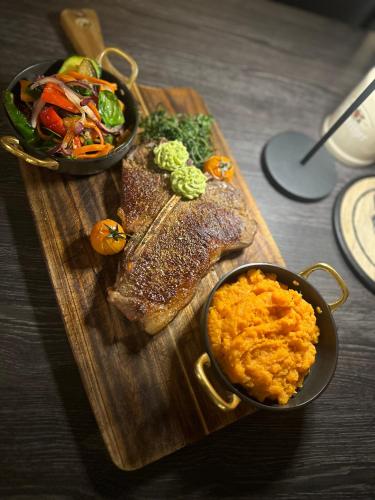 a wooden cutting board with meat and a bowl of food at Hotel "Central" Inh Carolin Krause in Bitterfeld