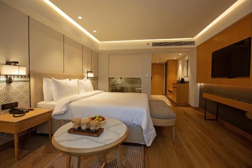 グワーハーティーにあるARISTA BY AMBITIONの大きなベッドとテーブルが備わるホテルルームです。
