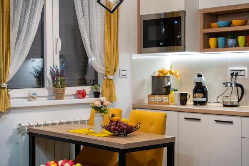 a kitchen with yellow chairs and a table with a bowl of fruit on it at SkyLine Lux 2 Apartman Zlatibor in Zlatibor