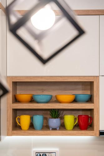 a shelf filled with colorful bowls and a window at SkyLine Lux 2 Apartman Zlatibor in Zlatibor
