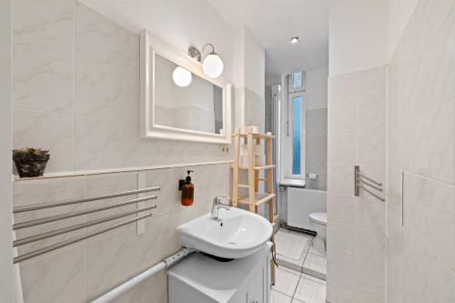 a white bathroom with a sink and a window at primeflats - Apartments Schillerpark Berlin-Wedding in Berlin