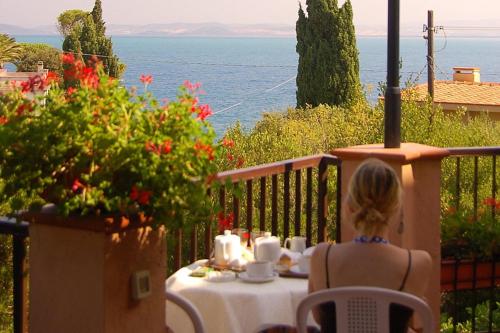 a woman sitting at a table in front of the ocean at Albergo Belvedere in Porto Santo Stefano