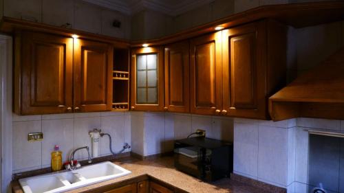 a kitchen with wooden cabinets and a sink and a microwave at غرفة هادئه بمنزل قريب من المطار 701 in Cairo
