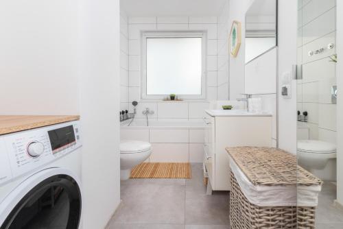 a white bathroom with a washing machine in it at Bright Apartment with Private Garden and Accepting Pets by Noclegi Renters in Gdańsk