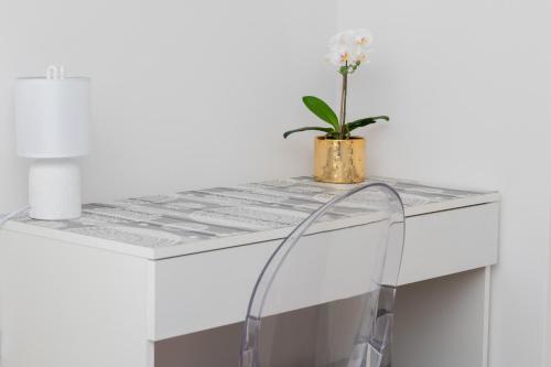 a white desk with a potted plant on it at Bright Apartment with Private Garden and Accepting Pets by Noclegi Renters in Gdańsk
