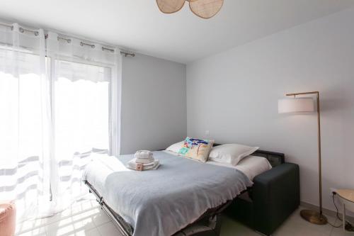 un lit dans une chambre blanche avec une fenêtre dans l'établissement A5 - Modern Studio 5 min to Sea - Pool & Garage, à Antibes