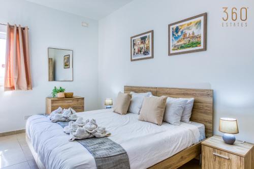 - une chambre dotée d'un grand lit avec des draps et des oreillers blancs dans l'établissement Beautiful 2BR Penthouse with Private Terrace & BBQ by 360 Estates, à San Pawl il-Baħar