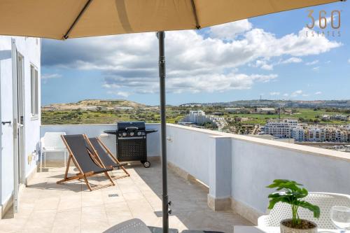 d'une terrasse avec un parasol et un grill sur un balcon. dans l'établissement Beautiful 2BR Penthouse with Private Terrace & BBQ by 360 Estates, à San Pawl il-Baħar