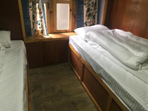 2 camas en una habitación pequeña con ventana en Tribeni Lodge Restaurant And Bar, en Phakding