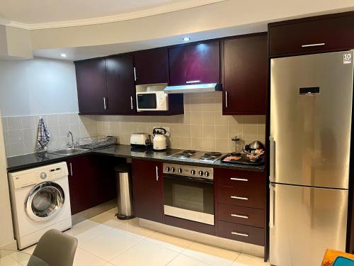 a kitchen with brown cabinets and a stainless steel refrigerator at Relaxing Seaside Apartment in scenic Houtbay in Cape Town