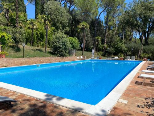a large blue swimming pool with chairs and trees at camere in Villa Luzi in Treia