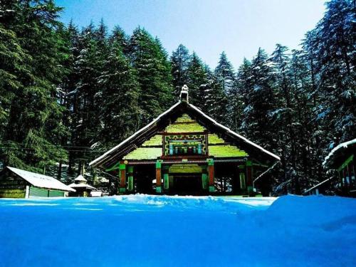 a building in the snow with trees in the background at Stargazing Glass Lodge Himachal Pradesh Thachi in Mandi