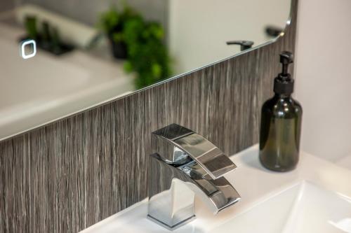 a bathroom sink with a faucet and a bottle of wine at Appin Holiday Homes -Caravans, Lodges, Shepherds Hut and Train Carriage stays in Appin
