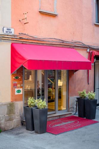a red awning in front of a building with plants at Hotel Centrale in Bologna