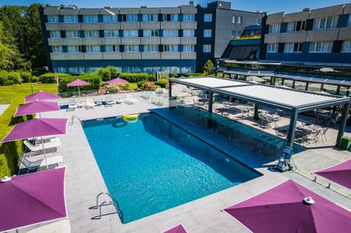 an overhead view of a swimming pool with purple umbrellas at Novotel Orléans Saint Jean de Braye in Saint-Jean-de-Braye
