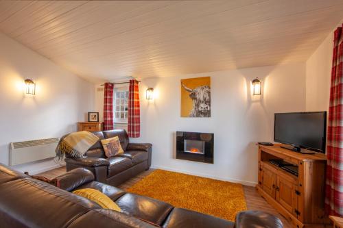 a living room with a couch and a television at Appin Holiday Homes -Caravans, Lodges, Shepherds Hut and Train Carriage stays in Appin