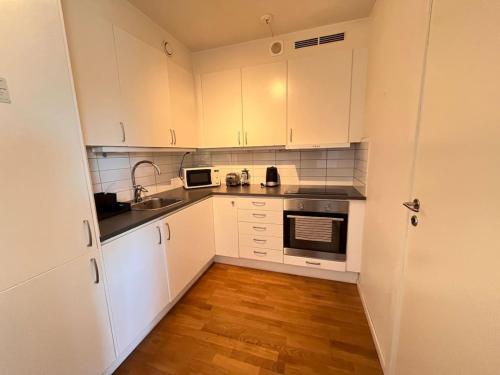 cocina con armarios blancos y suelo de madera en Cozy 1-Bed Nest in Lidingo, en Kottla