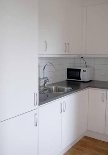 a white kitchen with a sink and a microwave at Lovely 1 bedroom flat in Larsberg, Lidingo in Kottla