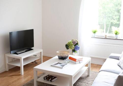 uma sala de estar branca com uma televisão e uma mesa de café branca em Lovely 1 bedroom flat in Larsberg, Lidingo em Kottla
