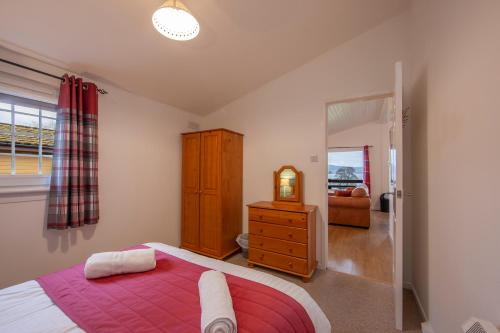 a bedroom with a bed and a dresser and a mirror at Appin Holiday Homes -Caravans, Lodges, Shepherds Hut and Train Carriage stays in Appin