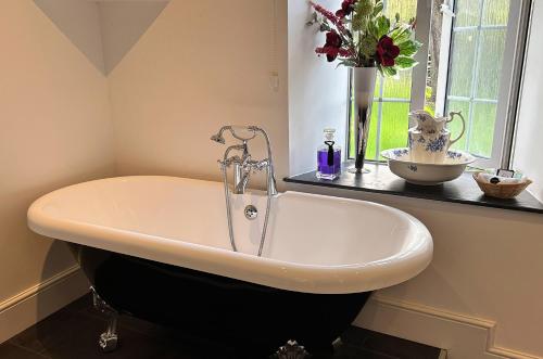 a bath tub in a bathroom with a vase of flowers at Exmoor Manor Guest House in Lynton