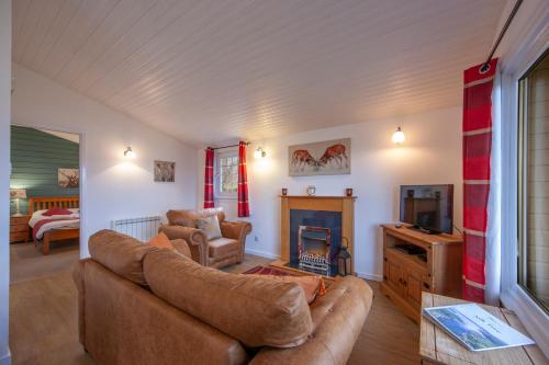 a living room with a couch and a fireplace at Appin Holiday Homes -Caravans, Lodges, Shepherds Hut and Train Carriage stays in Appin