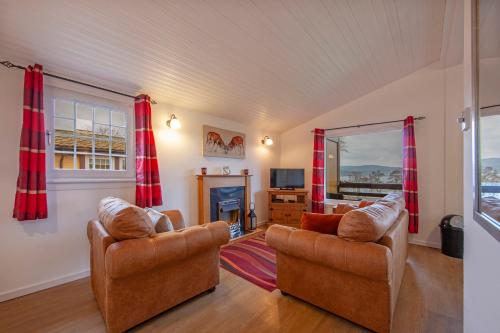 a living room with two chairs and a fireplace at Appin Holiday Homes -Caravans, Lodges, Shepherds Hut and Train Carriage stays in Appin