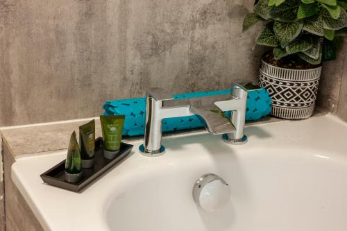 a white sink with a faucet and a plant at Appin Holiday Homes -Caravans, Lodges, Shepherds Hut and Train Carriage stays in Appin
