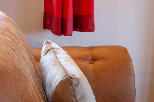 a brown couch with a pillow in front of a window at Appin Holiday Homes -Caravans, Lodges, Shepherds Hut and Train Carriage stays in Appin