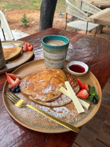 a plate of pancakes with fruit and a cup of coffee at Akasha suites in Doradal