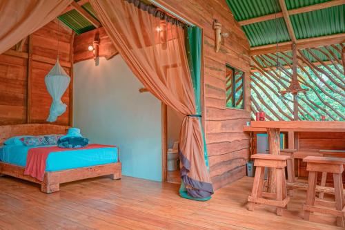 a bedroom in a log cabin with a bed and a table at La Tigra Rainforest Lodge in Fortuna
