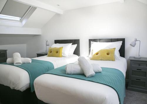 two beds in a bedroom with white and yellow pillows at White Cottage deluxe 2 bedroom apartment in Grassington