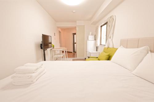 Mi-APT SHIRO في طوكيو: غرفة نوم بسرير ابيض عليها مناشف