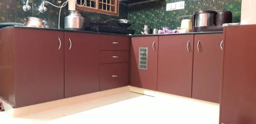 a kitchen with red cabinets in a kitchen at Paradise Home Stay Pondicherry Luxury Stay with Private Swimming Pool in Auroville