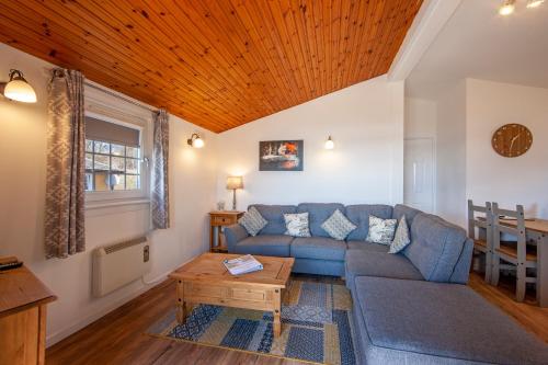 a living room with a blue couch and a table at Appin Holiday Homes -Caravans, Lodges, Shepherds Hut and Train Carriage stays in Appin